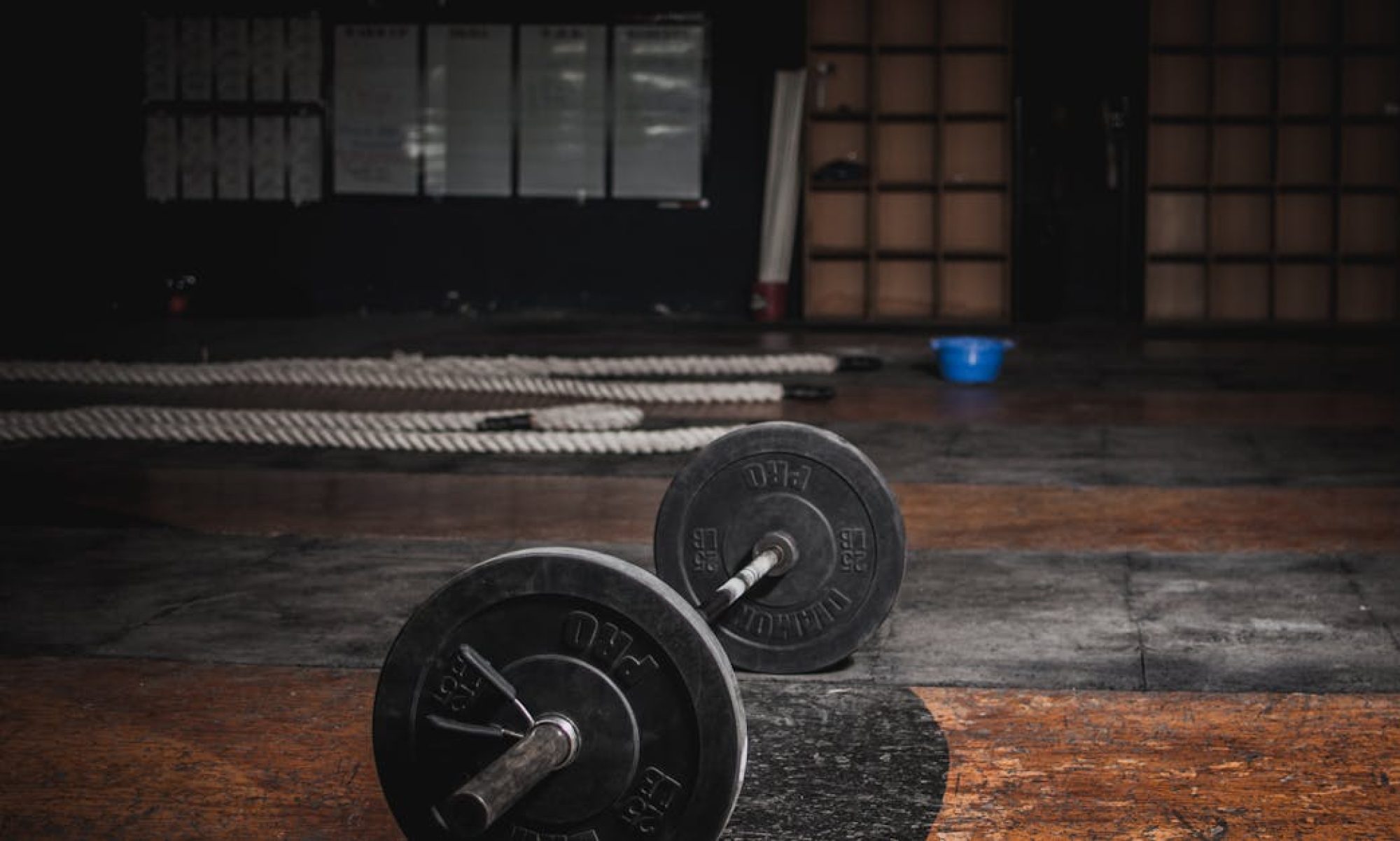 A lone barbell rests in an empty, dimly lit gym, emphasizing strength and solitude.