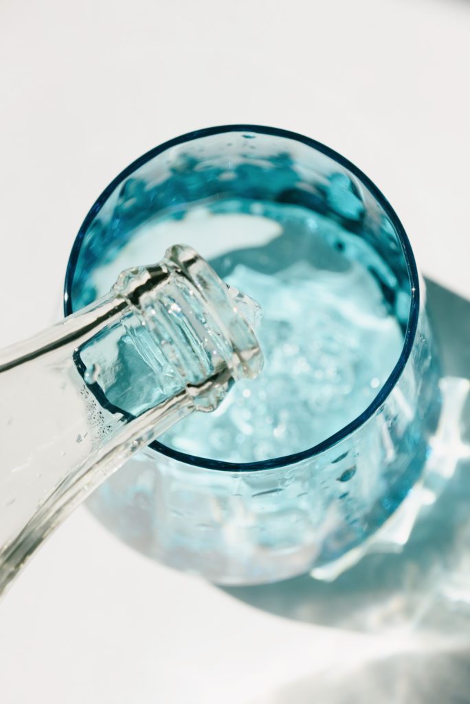 pexels-photo-8054440-8054440 Close-up of water being poured into a blue glass in a sunny setting.